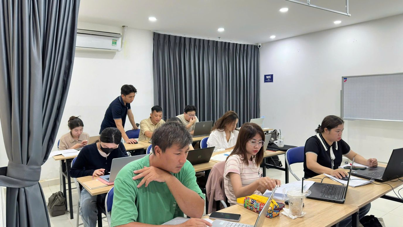 Giảng viên hướng dẫn nhóm học viên thực hành trên máy tính trong lớp