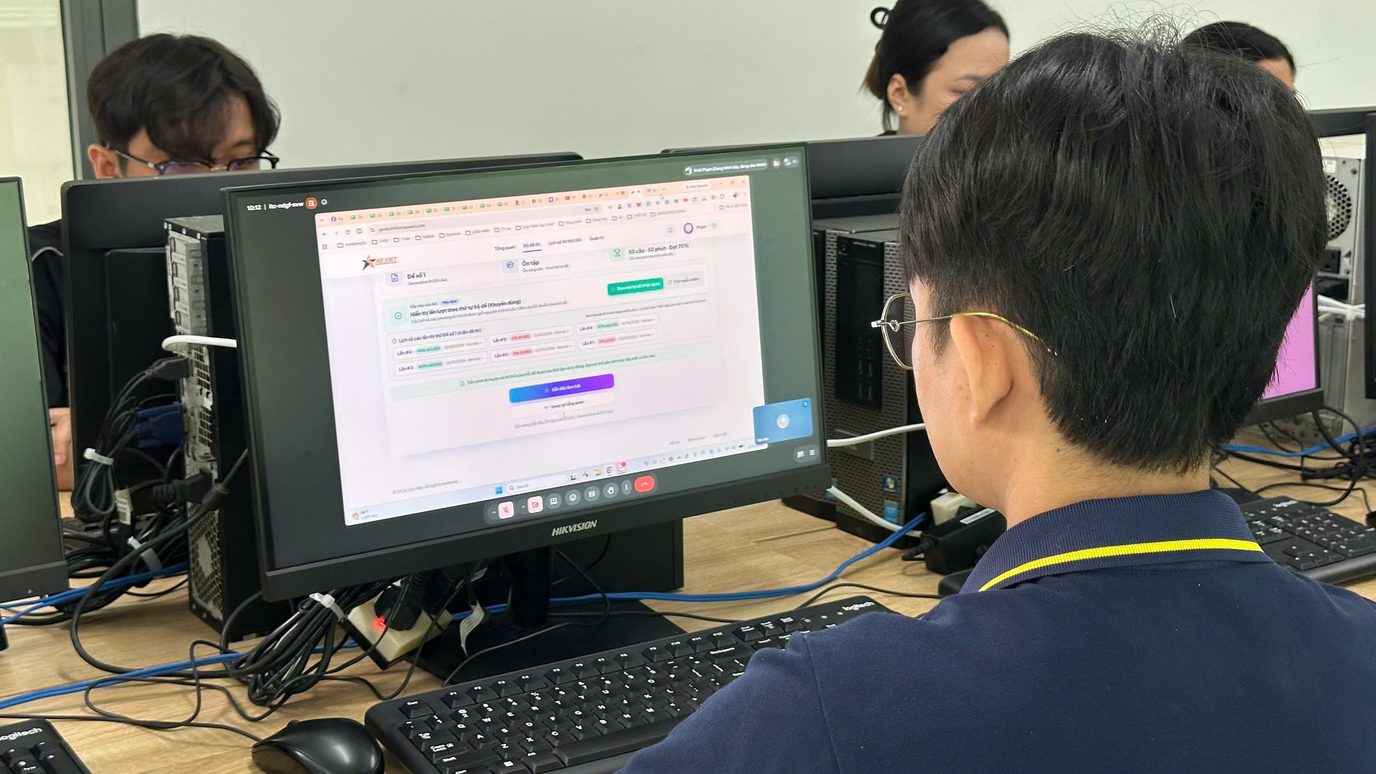 Giảng viên trao đổi cùng học viên cạnh màn hình máy tính